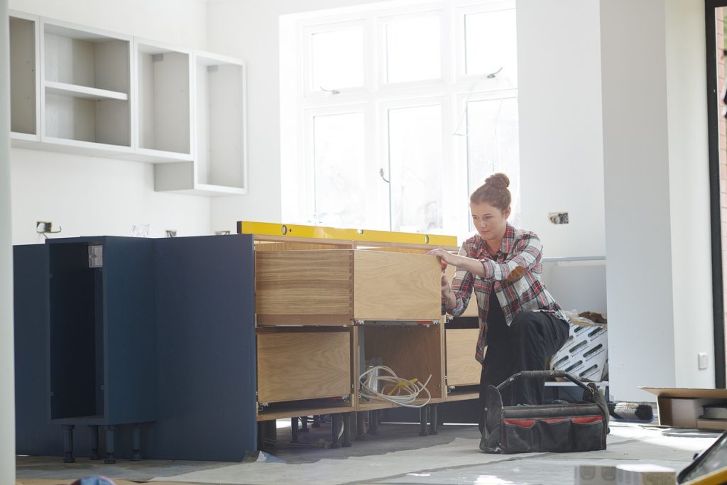 a female kitchen fitter prepping cupboards for worktop