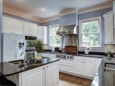 Elegant kitchen with white cabinets, granite countertops, and stainless steel appliances. Featuring a center island, large windows, and hardwood flooring.