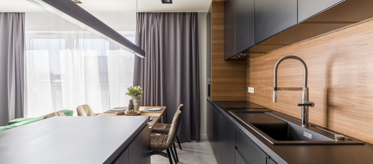 A sleek, modern kitchen featuring black cabinets, wood accents, and a stylish dining area with natural light from large windows, creating a sophisticated and inviting space.