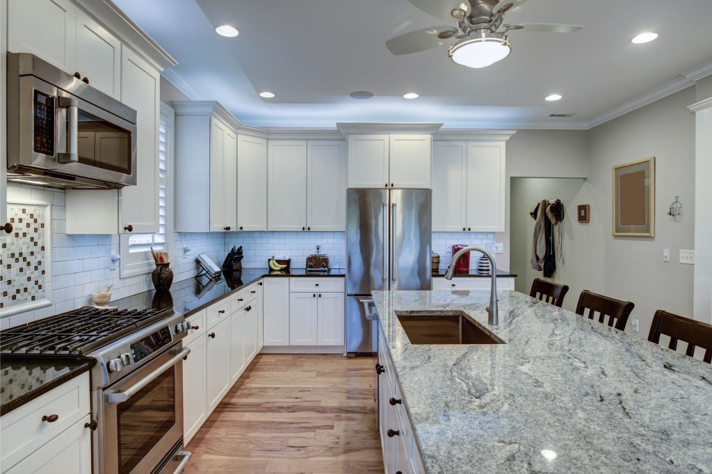 A modern, spacious kitchen featuring a large granite island with seating, white cabinets, and stainless steel appliances, providing a functional and elegant cooking space.