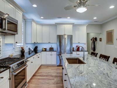 A modern, spacious kitchen featuring a large granite island with seating, white cabinets, and stainless steel appliances, providing a functional and elegant cooking space.