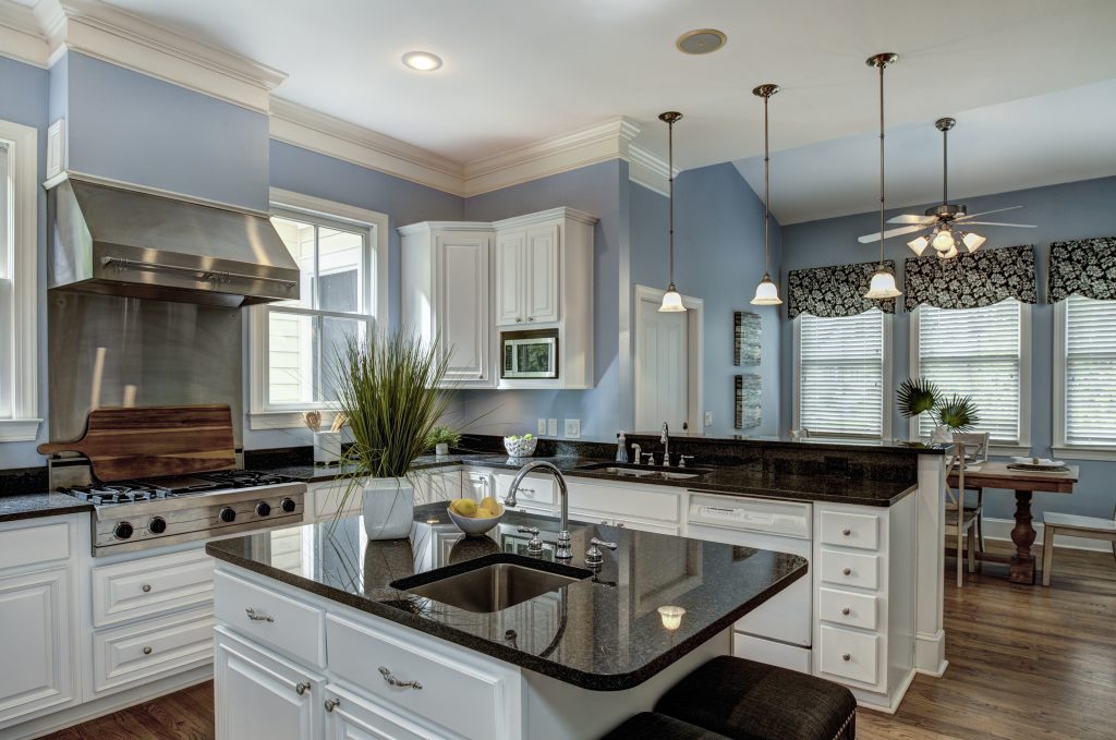 A sophisticated kitchen featuring granite countertops, white cabinets, stainless steel appliances, and stylish pendant lighting, creating a modern and inviting space.