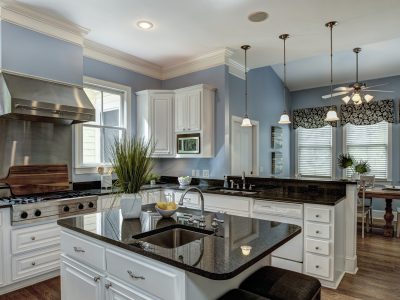 A sophisticated kitchen featuring granite countertops, white cabinets, stainless steel appliances, and stylish pendant lighting, creating a modern and inviting space.