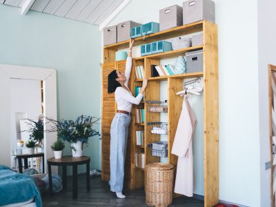 Woman organizing storage boxes on wooden shelves
