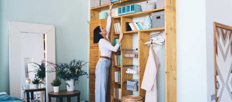 Woman organizing storage boxes on wooden shelves