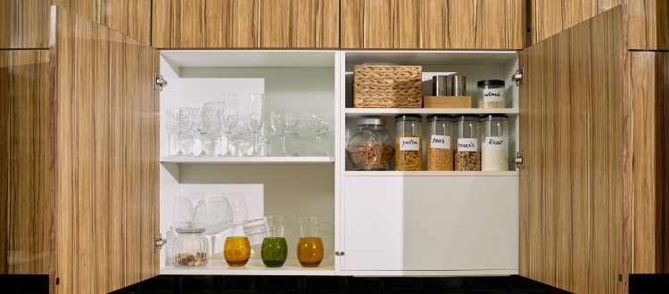 Open kitchen cabinet with glassware and jars