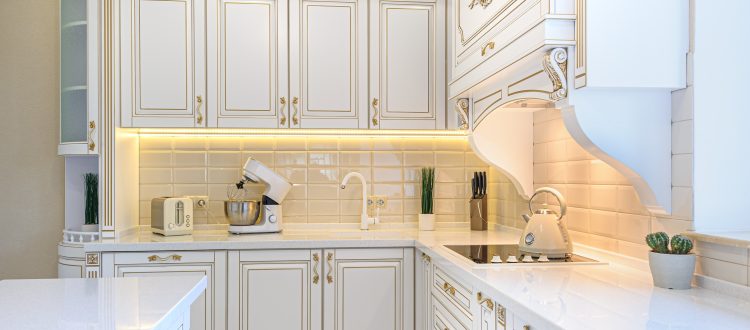 White kitchen cabinets with gold trim and appliances