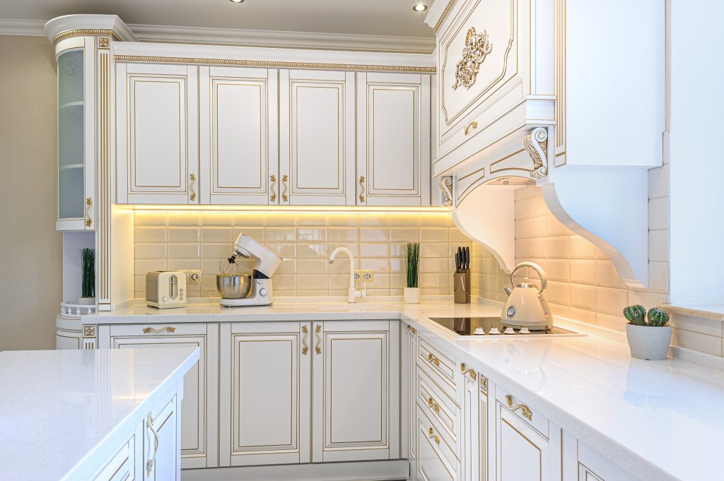 White kitchen cabinets with gold trim and appliances