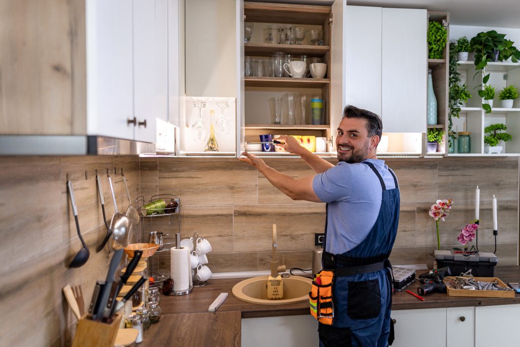 Man installing white kitchen cabinets