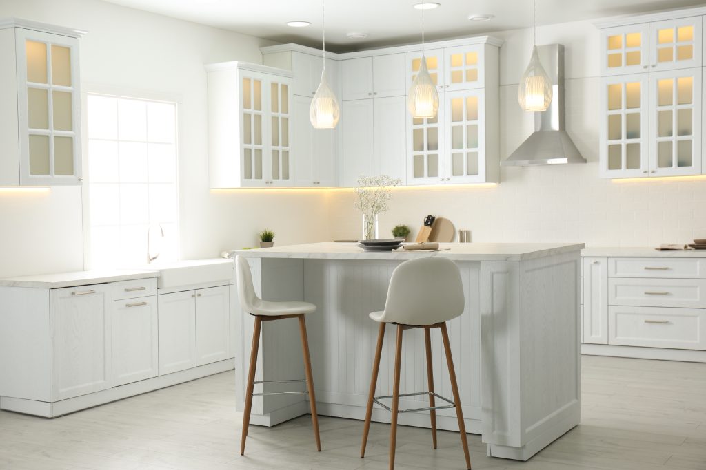 White kitchen island with stools and pendant lights